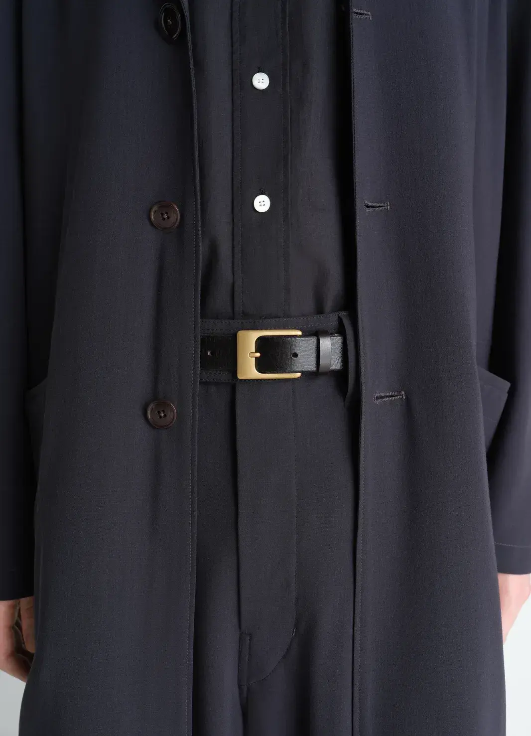 Close detail of polished metal hardware and stitched leather edging